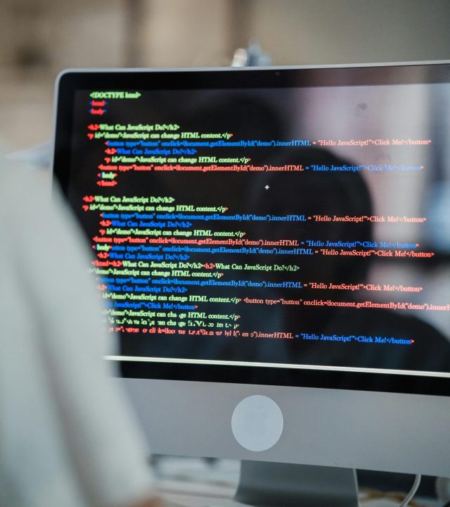 A close-up of a computer screen displaying colorful coding script in an office environment.